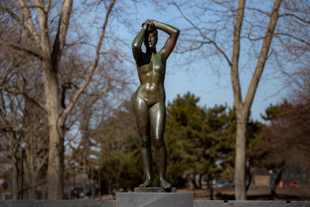 Gerhard Marcks' bronze Maja sculpture on a sunny day - female nude, arms raise overhead