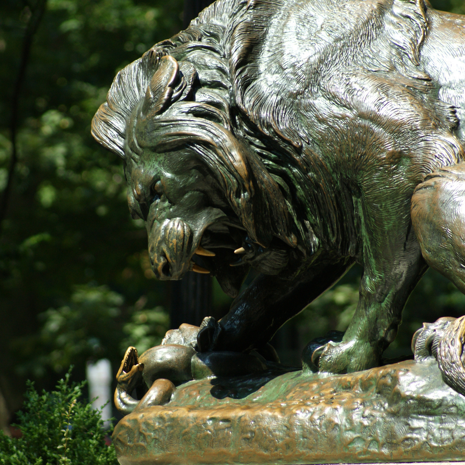 Close-up of a large statue of a roaring lion stepping on a snake.