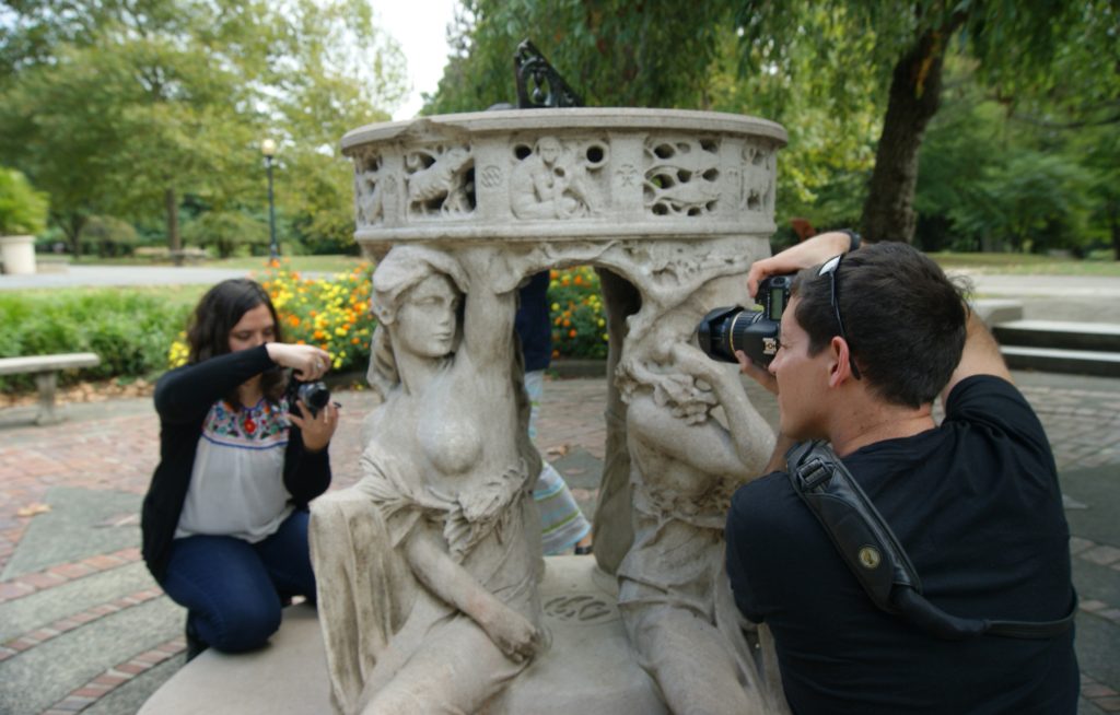 An outdoor sculpture photography workshop: a man and a woman using their camera to photograph Alexander Stirling Calder's limestone "Sundial" sculpture in Philadelphia's Fairmount Park